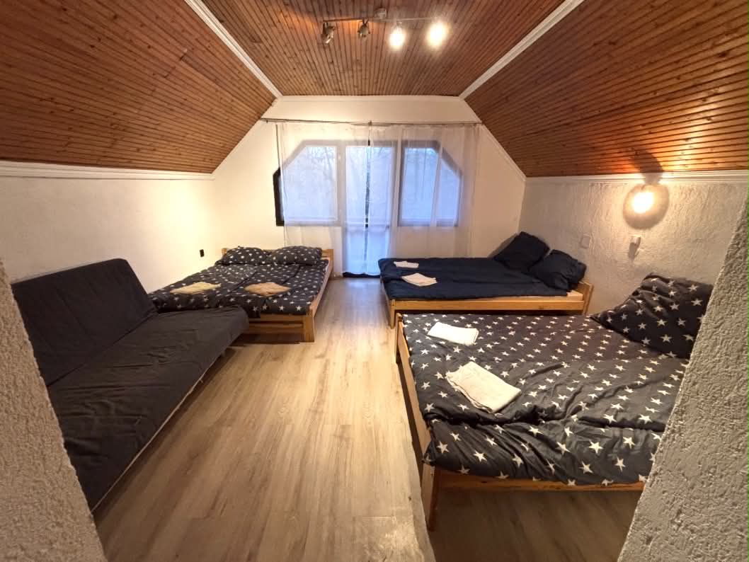 Vendégház tágas, fa mennyezetű szobája több ággyal